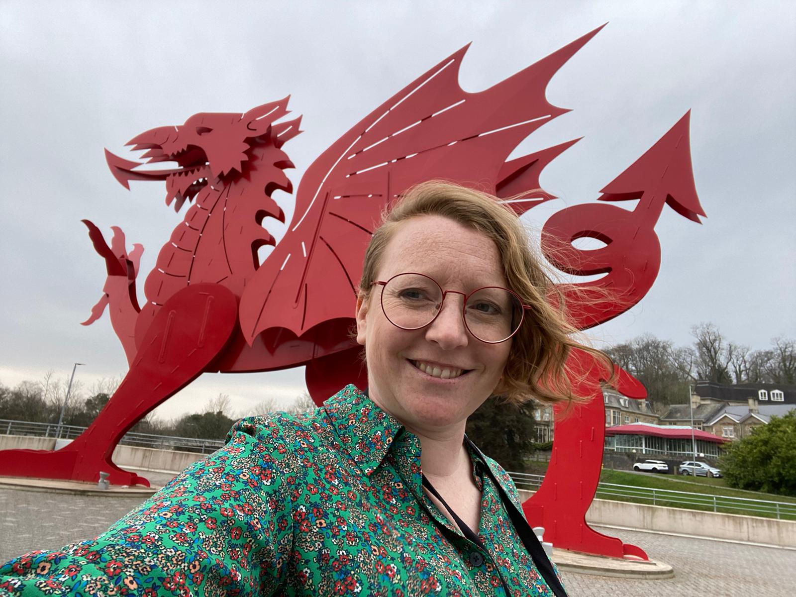 Grasshopper Director, Clare Jones, takes a selfie in front of a large, red Welsh Dragon sculpture